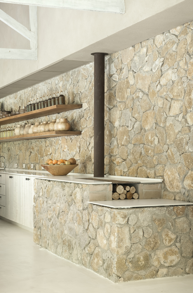 cocina de estilo rústico moderno conservando parte de la piedra original y con muebles en color blanco